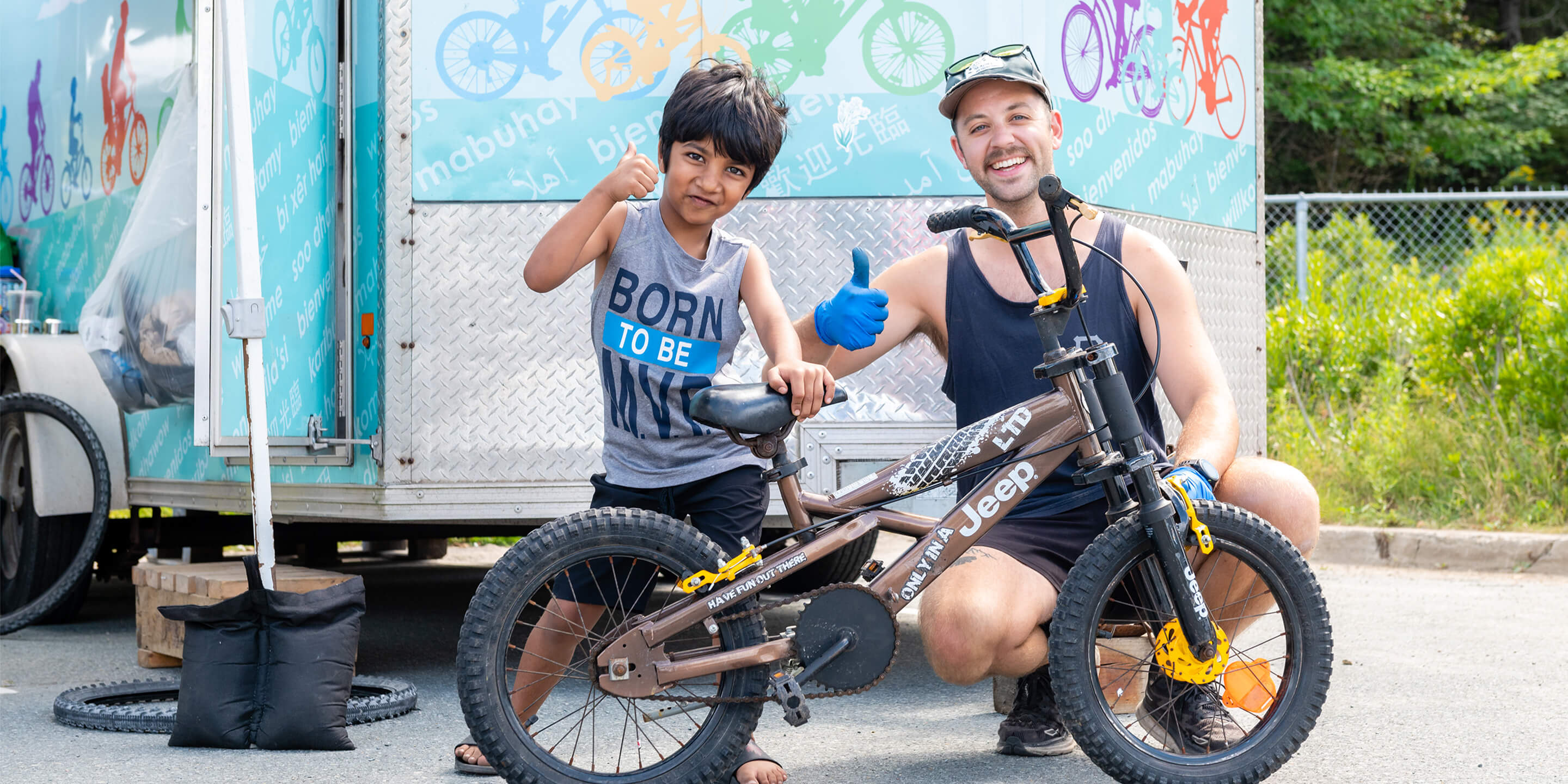 Young boy and staff giving a thumbs up, posing infront of a bicycle